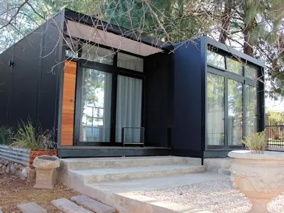 a black house with glass windows and stairs at TWO Prefab Living - Luxury bungalows in Dullstroom