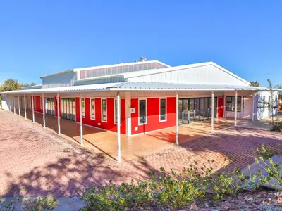 a red building on the beach next to a field at Thuto Centre Conferencing & Bush Lodge in Bela-Bela