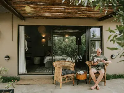 a man sitting in a chair on a patio at Rhino's Rest Private Luxury Villa in Hoedspruit