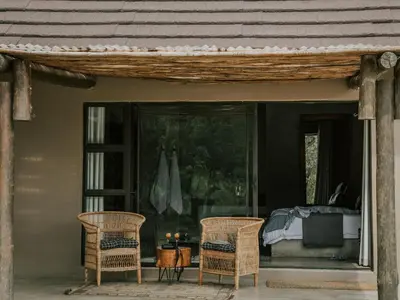 a porch with two chairs and a bed at Rhino's Rest Private Luxury Villa in Hoedspruit