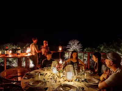 a group of people sitting around a table at night at Rhino's Rest Private Luxury Villa in Hoedspruit