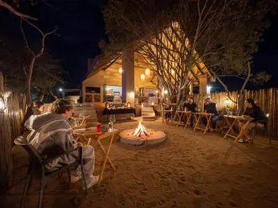a group of people sitting around a fire pit at night at Rhino's Rest Private Luxury Villa in Hoedspruit