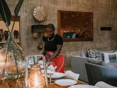a woman standing next to a table in a restaurant at Rhino's Rest Private Luxury Villa in Hoedspruit