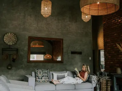 a woman sitting on a couch reading a book at Rhino's Rest Private Luxury Villa in Hoedspruit