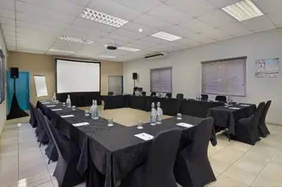 a conference room with tables and chairs and a screen at Protea Hotel by Marriott Polokwane Landmark in Polokwane