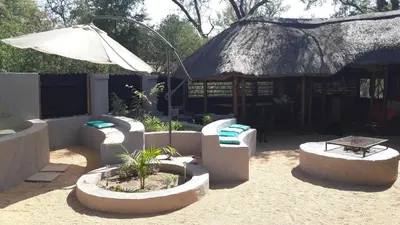 a patio with couches and a table and an umbrella at Off Beat Safaris Bush Lodge in Hoedspruit