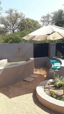 a patio with an umbrella and a swimming pool at Off Beat Safaris Bush Lodge in Hoedspruit