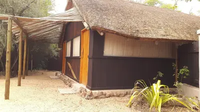 a small black building with a thatched roof at Off Beat Safaris Bush Lodge in Hoedspruit