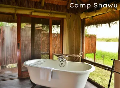 a bath tub in a room with a large window at Shishangeni Lodge In Kruger National Park in Komatipoort