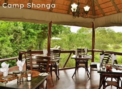a restaurant with tables and chairs on a deck at Shishangeni Lodge In Kruger National Park in Komatipoort