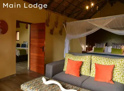 a bedroom with a bed with a canopy and a couch at Shishangeni Lodge In Kruger National Park in Komatipoort
