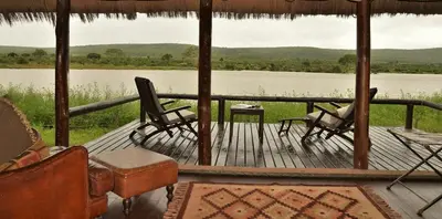 a porch with chairs and a view of a lake at Shishangeni Lodge In Kruger National Park in Komatipoort