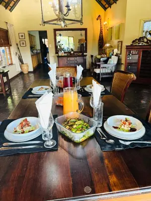 a wooden table with plates of food on it at Khandizwe Kruger Villa in Malelane