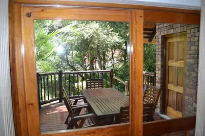 a porch with a table and chairs on a deck at Kruger Park Lodge - Golf Safari SA in Hazyview