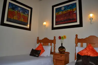 a hotel room with two beds and a vase of flowers at Kruger Park Lodge - Golf Safari SA in Hazyview