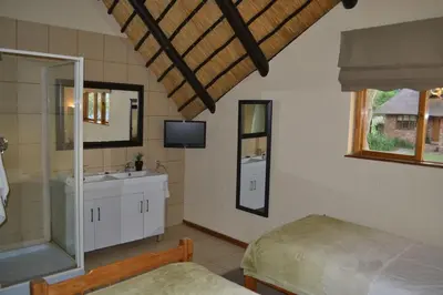 a bedroom with a bed and a sink and a mirror at Kruger Park Lodge - Golf Safari SA in Hazyview