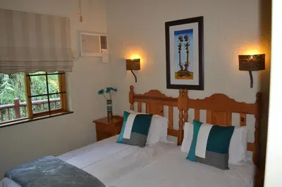 a bedroom with two beds and two windows at Kruger Park Lodge - Golf Safari SA in Hazyview