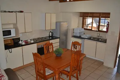 a kitchen with a wooden table and chairs and a kitchen with a stove at Kruger Park Lodge - Golf Safari SA in Hazyview
