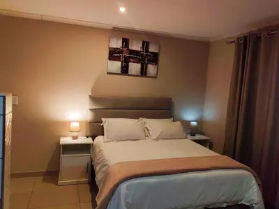 a bedroom with a large bed with two night stands at Makobaneng Guesthouse in Ga-Raphokola