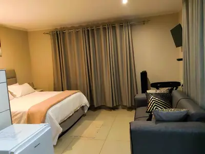 a hotel room with a bed and a couch at Makobaneng Guesthouse in Ga-Raphokola