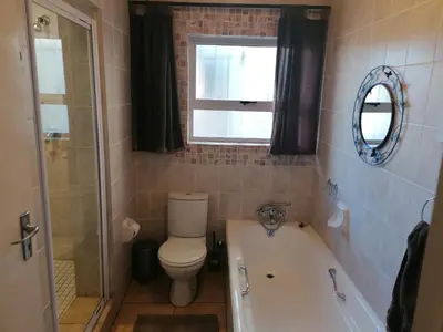 a bathroom with a toilet and a tub and a window at Inviting 3-Bed House in Kempton Park in Kempton Park