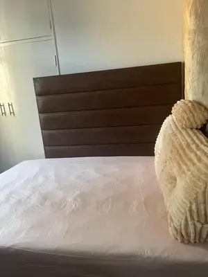 a white bed with a wooden headboard in a room at Just a Room in Pretoria