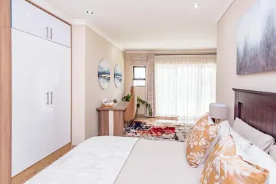 a bedroom with a large bed and a bathroom at 150 Jacaranda Guesthouse in Midrand