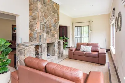 a living room with two leather couches and a stone fireplace at 150 Jacaranda Guesthouse in Midrand