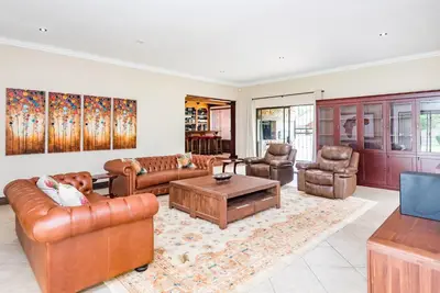 a living room with leather furniture and a table at 150 Jacaranda Guesthouse in Midrand