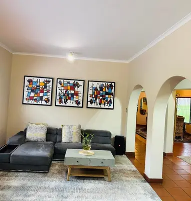 a living room with a black leather couch and stained glass windows at 150 Jacaranda Guesthouse in Midrand