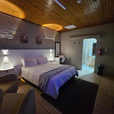 a bedroom with a bed and a couch and a chair at ZUCH Accommodation at Pafuri Self Catering in Polokwane