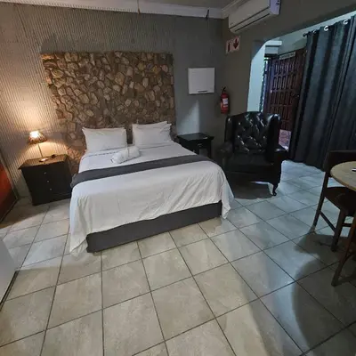 a bedroom with a large bed and a chair at ZUCH Accommodation at Pafuri Self Catering in Polokwane
