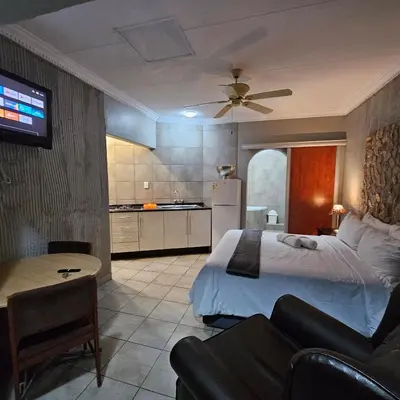 a bedroom with a bed and a couch and a kitchen at ZUCH Accommodation at Pafuri Self Catering in Polokwane