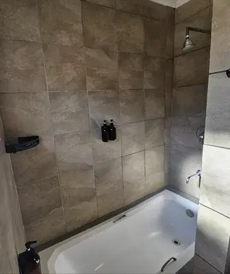 a bathroom with a bath tub with a shower at ZUCH Accommodation at Pafuri Self Catering in Polokwane