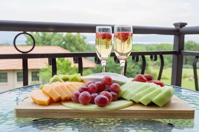 a plate of fruit on a table with two glasses of champagne at Three Oaks and an Aloe Boutique Hotel in Hartbeespoort