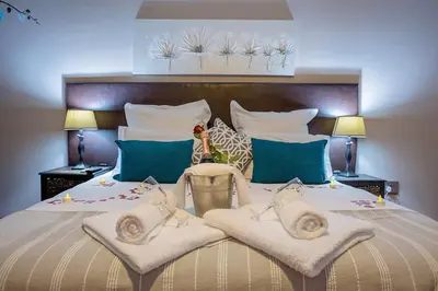 a bedroom with a large bed with two chairs at Three Oaks and an Aloe Boutique Hotel in Hartbeespoort