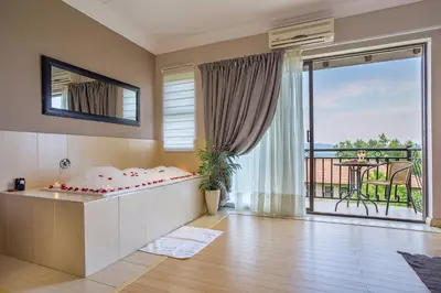 a bedroom with a bed and a balcony with a view at Three Oaks and an Aloe Boutique Hotel in Hartbeespoort