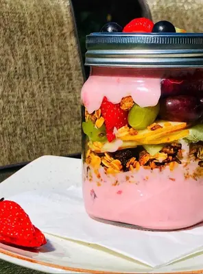a jar of food with fruit and berries on a plate at Three Oaks and an Aloe Boutique Hotel in Hartbeespoort