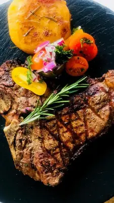 a piece of meat with vegetables on a black plate at Three Oaks and an Aloe Boutique Hotel in Hartbeespoort