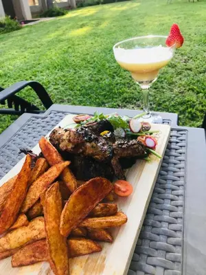 a plate of food with french fries and a drink at Three Oaks and an Aloe Boutique Hotel in Hartbeespoort