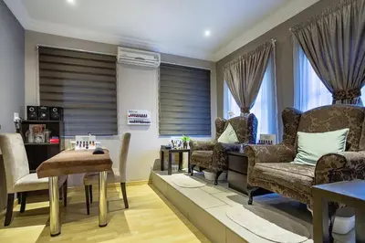 a living room with chairs and a table and windows at Three Oaks and an Aloe Boutique Hotel in Hartbeespoort