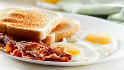 a white plate with eggs and bacon and toast at Tzaneen Arborpark Lodge in Tzaneen