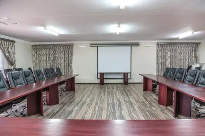 a conference room with desks and chairs and a whiteboard at Tzaneen Arborpark Lodge in Tzaneen