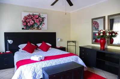 a bedroom with a large bed with red pillows at Tzaneen Arborpark Lodge in Tzaneen