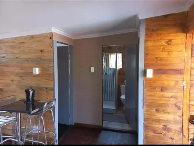 a room with wooden walls and a table and chairs at Amaroks self catering units in Sabie