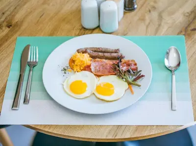 a plate of eggs bacon and sausage on a table at Wilson Guest House in Groblersdal