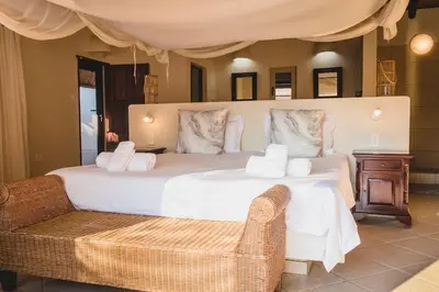 a bedroom with a large white bed and a chair at Amazing mountain views! Solar powered! in Hoedspruit