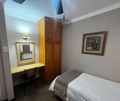 a bedroom with a bed and a desk with a mirror at 3-Bedroom House, Greenway Woods, White River in White River