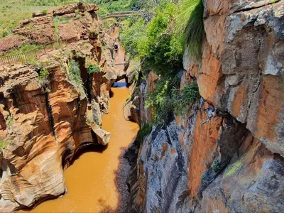 a river between two cliffs with a bridge in the background at Masorini Bush Lodge & Safari Tents in Phalaborwa