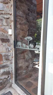a glass door of a stone wall with a table with chairs at The Shoe Guest House in Draasloot
